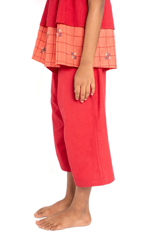 Girl wearing a red outfit with a matching top and pants on a white background