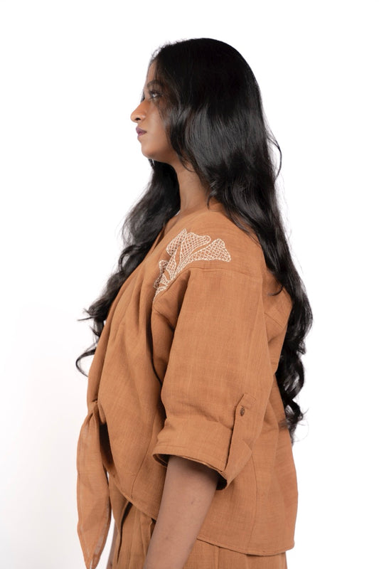 Woman wearing a brown outfit with lace details on a white background