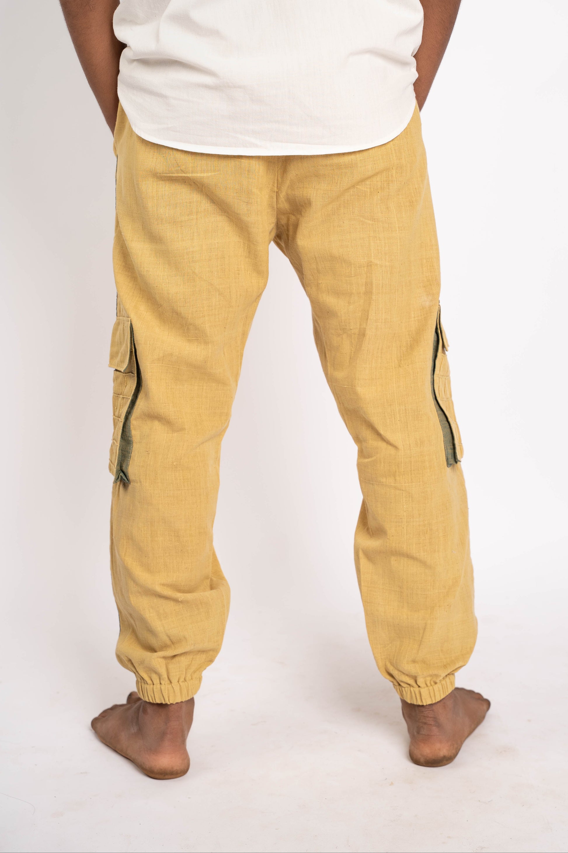 Person wearing mustard yellow cargo pants and a white shirt on a white background
