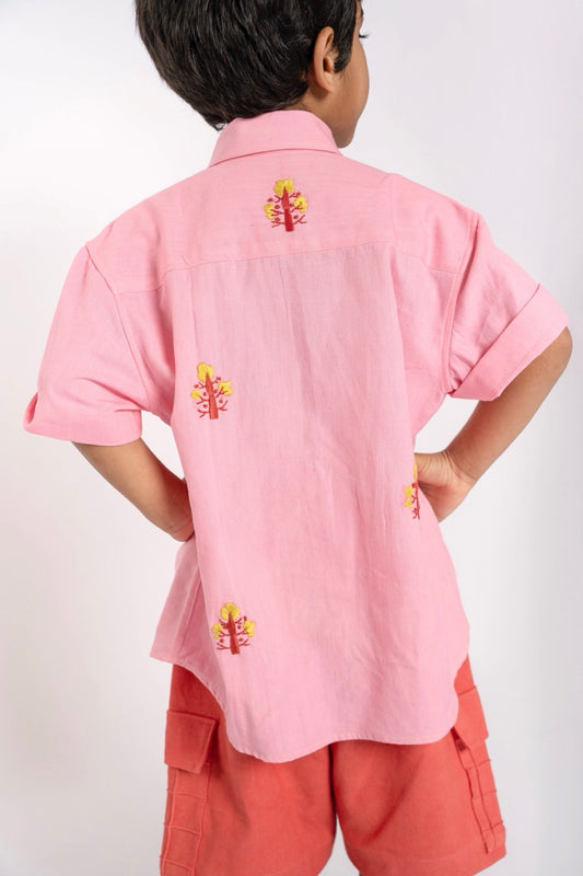 Child wearing a pink shirt with floral designs on a white background