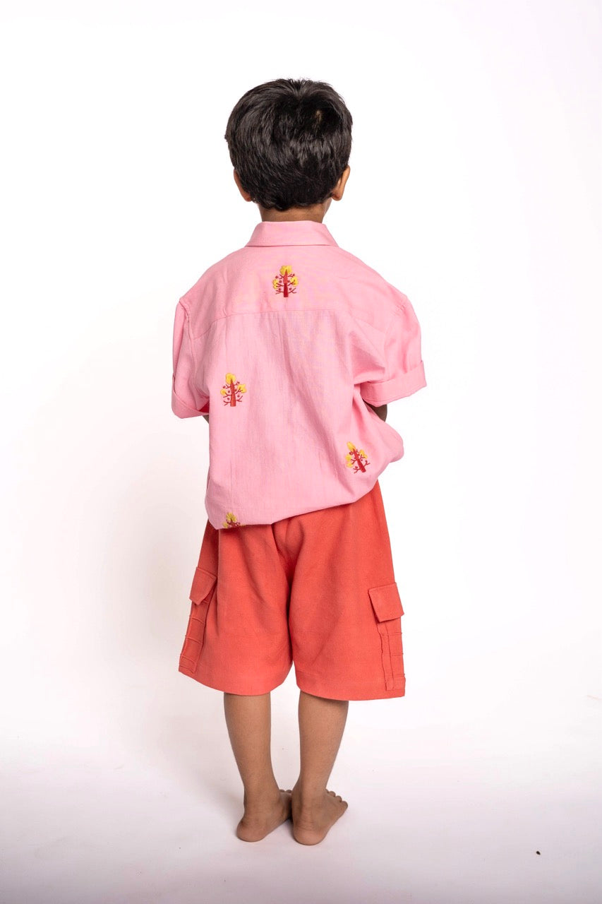 Child wearing a pink shirt and orange shorts on a white background