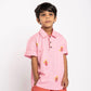 Child wearing a pink polo shirt with floral embroidery and peach shorts on a white background
