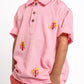 Child wearing a pink polo shirt with floral embroidery on a white background