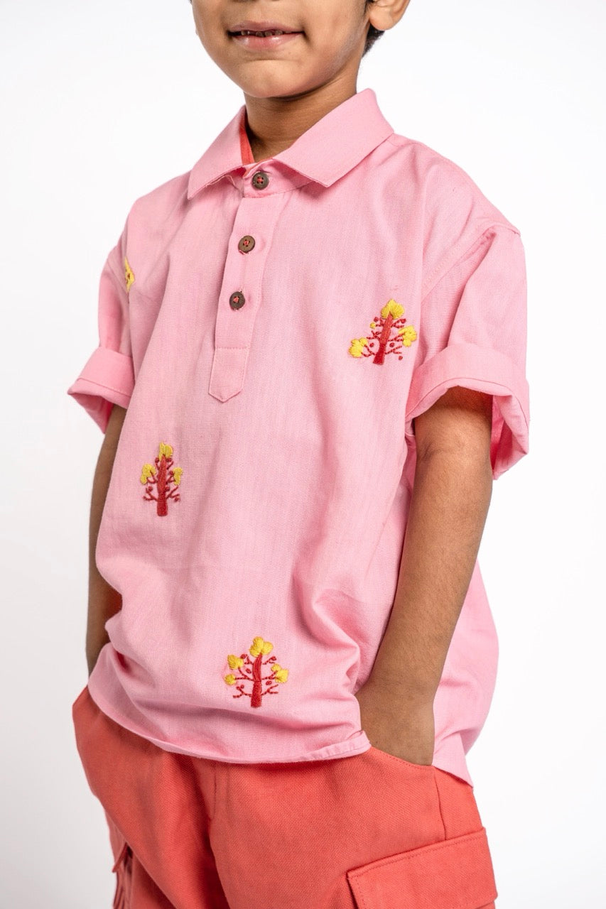 Child wearing a pink polo shirt with floral embroidery on a white background