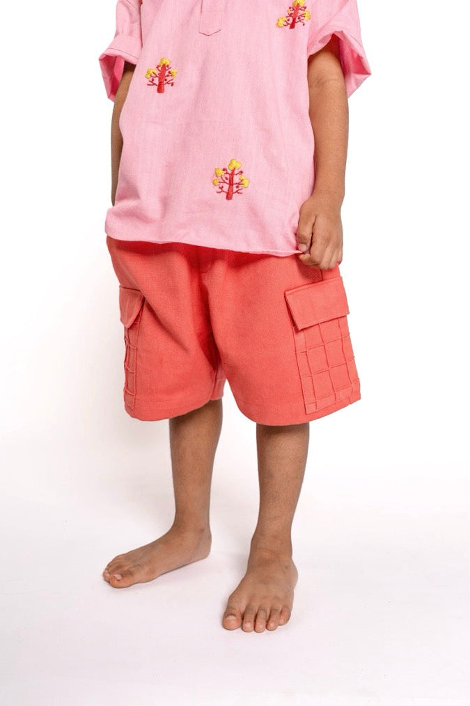 Child wearing a pink outfit with floral embroidery on a white background