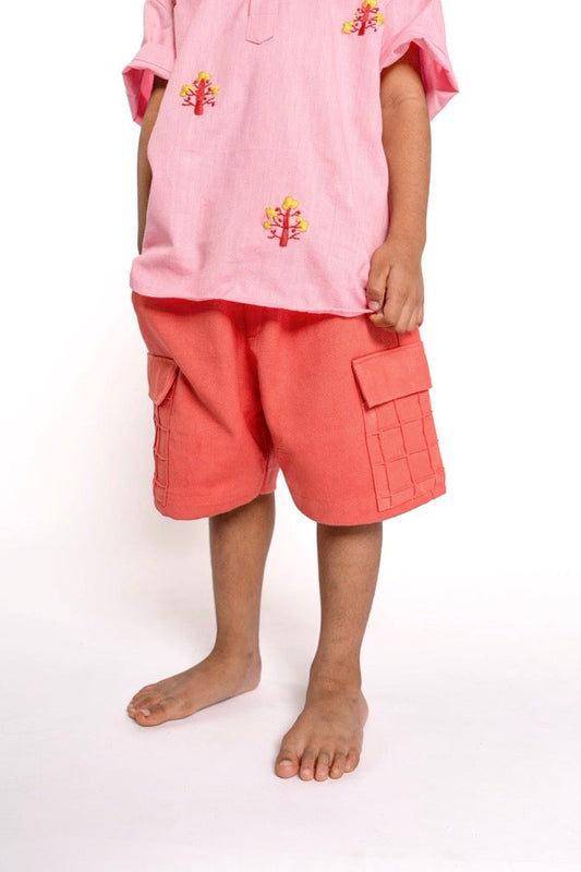 Child wearing a pink outfit with floral embroidery on a white background
