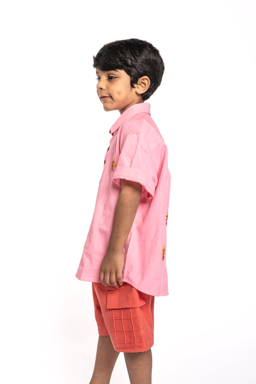 Child wearing a pink shirt and red shorts on a white background