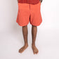 Person wearing a red shirt and orange shorts on a white background