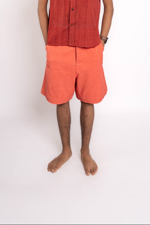 Person wearing a red shirt and orange shorts on a white background
