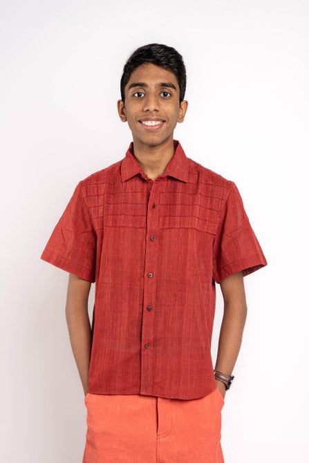 Person wearing a red shirt and orange shorts on a white background