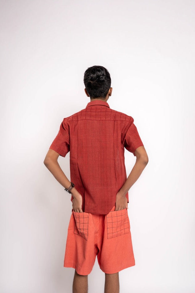 Person wearing a red shirt and orange shorts on a white background