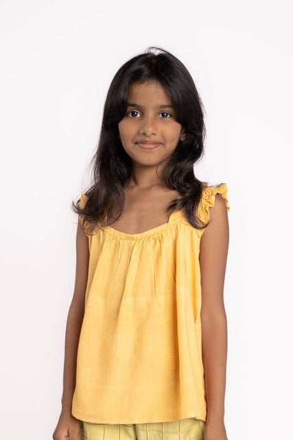 Young girl wearing a yellow top and shorts on a white background