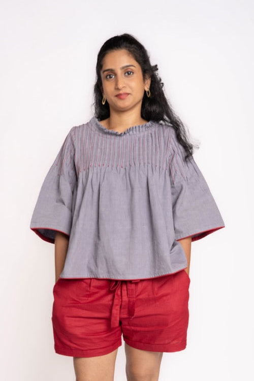 Woman wearing a gray top and red shorts on a white background
