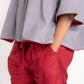 Woman wearing a gray top with red trim and red shorts on a white background