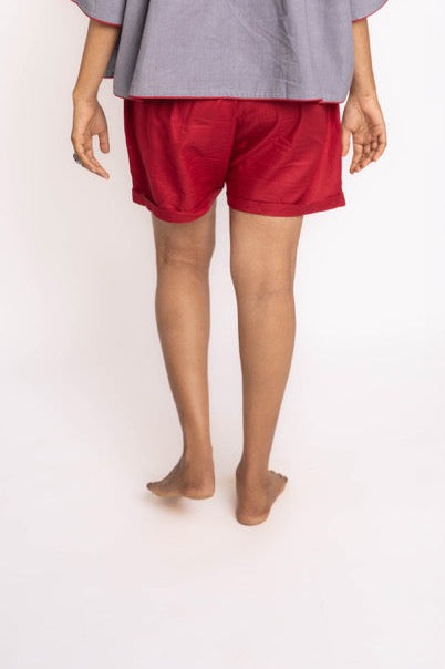 Person wearing a gray shirt and red shorts on a white background