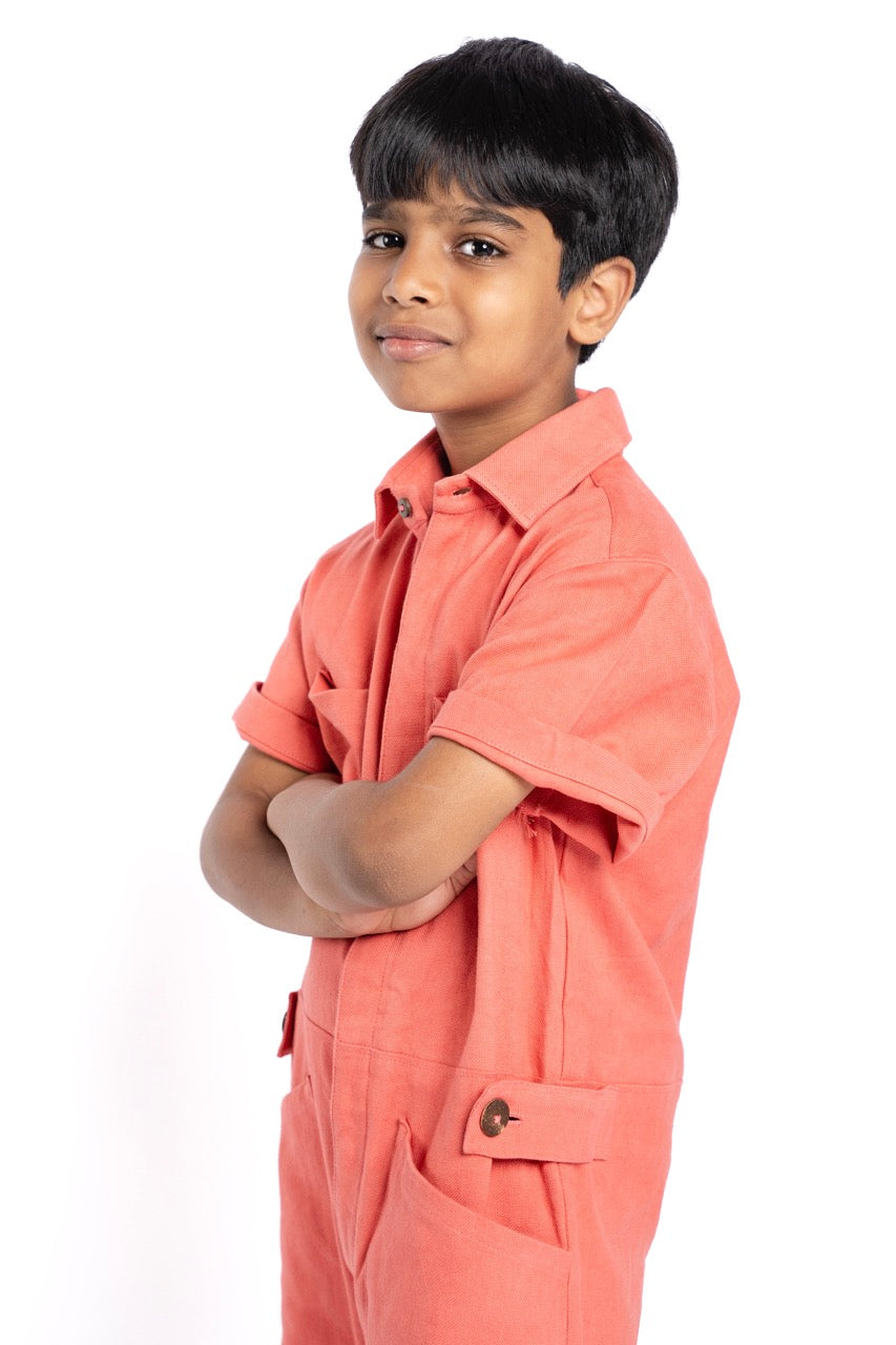 Young boy wearing a peach-colored shirt and pants on a white background