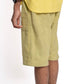Person wearing light green shorts and a yellow top on a white background