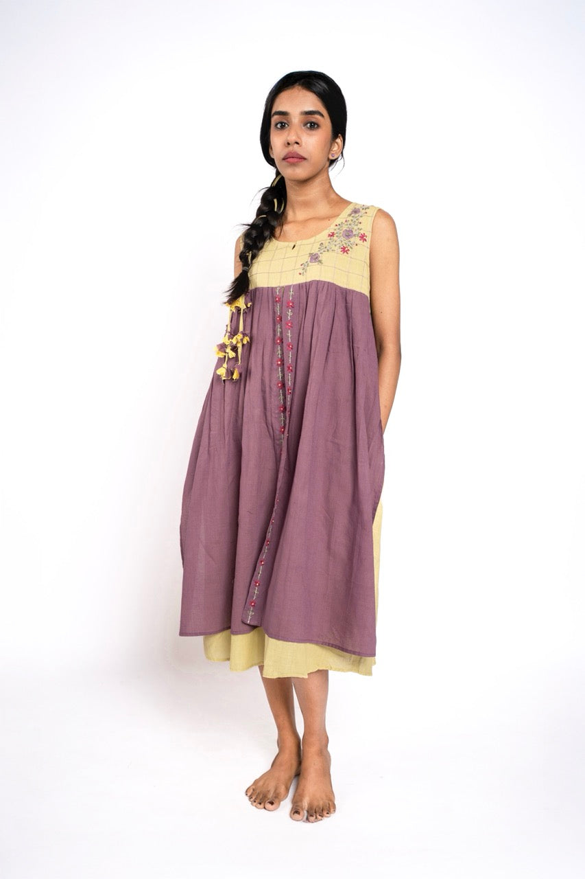 Woman wearing a two-tone dress with floral embroidery on a white background