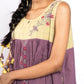 Woman wearing a yellow and purple traditional outfit with floral embroidery.